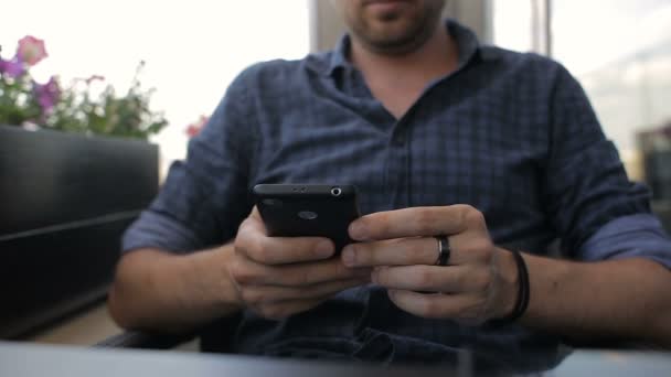 Man får sms på en smartphone i ett café — Stockvideo