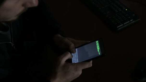 Hacker mit einem Smartphone-Gerät zu entführen. Grüner Code hackt Text, der sich überlappt — Stockvideo