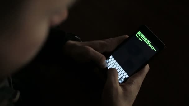 Hacker utilizzando un dispositivo smartphone per dirottare. Codice verde hacking testo sovrapposizione — Video Stock