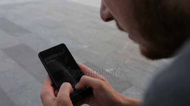 Хакер вламывается в wifa с помощью телефона в парке на скамейке запасных — стоковое видео