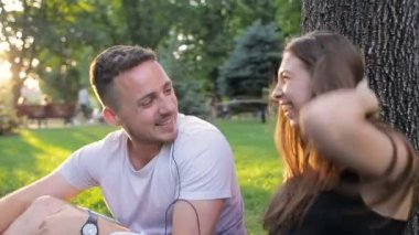 Adam ve kız bir ağacın altında oturup park müzik dans