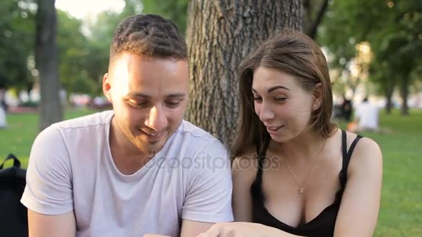 O cara e a menina estão assistindo piadas no telefone e rindo — Vídeo de Stock