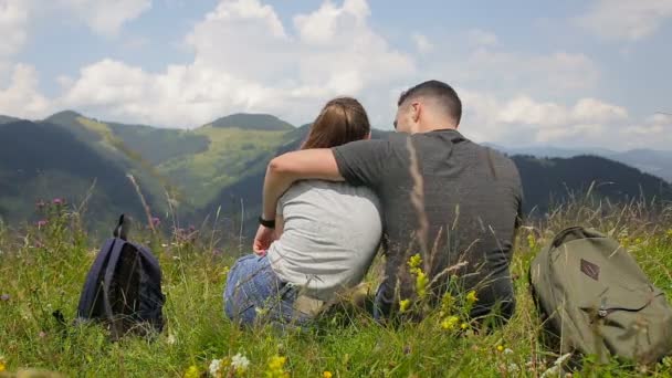 観光客の若いカップルは、雲の背景に山で休んでいます。 — ストック動画