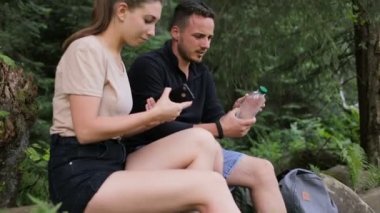 Ormanda kayalar ve içme suyu üzerinde dinlenme backpackers genç bir çift