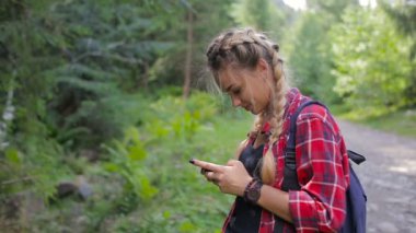 Mutlu kız smartphone cep telefonu ile orman, mesaj sms içinde ayakta