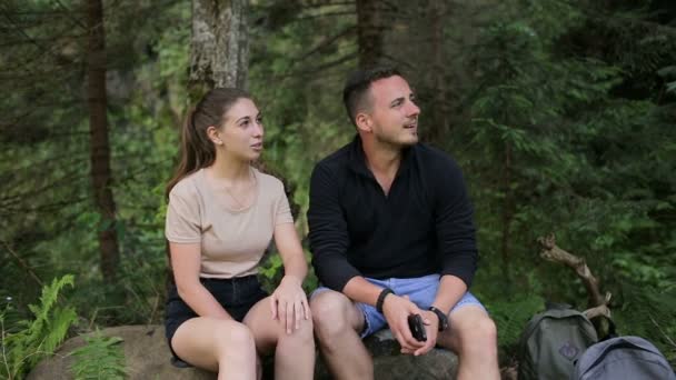 Una joven pareja de turistas descansan bajo un árbol en las piedras — Vídeos de Stock