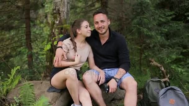 Una giovane coppia di backpackers che riposano nel bosco e guardano la telecamera — Video Stock