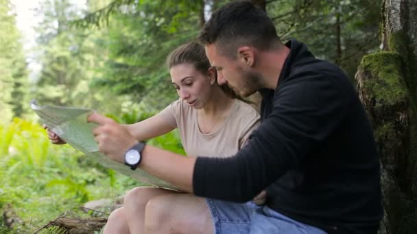 Jong (echt) paar wandelaars in het bos op zoek naar de routekaart — Stockvideo