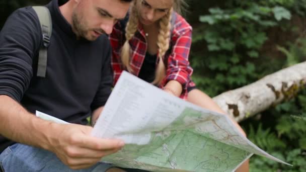 一个男人和一个女孩在树林里寻找一条路与地图 — 图库视频影像