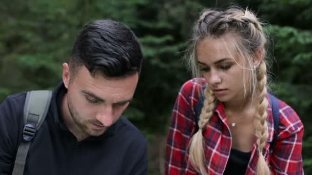 Un ragazzo e una ragazza nel bosco stanno cercando una strada con una mappa — Video Stock