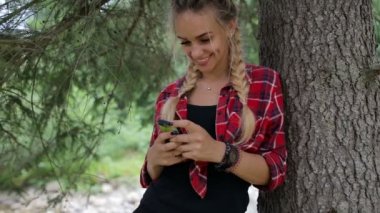 Mutlu kız smartphone cep telefonu ile orman, mesaj sms içinde ayakta