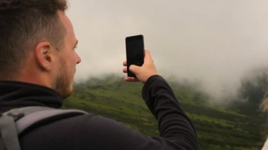 Genç yürüyüşçü fotoğrafta akıllı telefon ile dağlarda