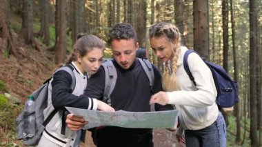 İki hatun ve bir adam bir harita ormandaki bir yol bulmak için kullanma