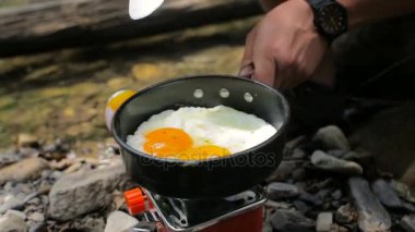 Mens eller üzerinde kamp Sobalar kamp içinde bir tavada kızarmış yumurta ilave edin