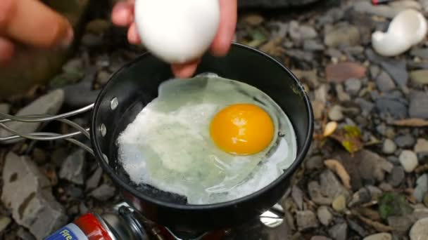 Турист готовит яйца к завтраку в кемпинге — стоковое видео