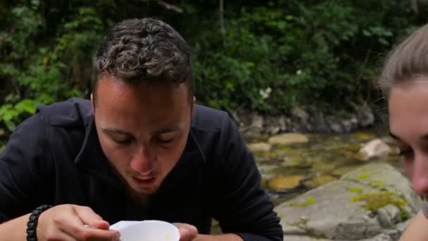 Туристы едят яйца в палатках на берегу реки — стоковое видео