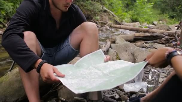 Hikers with a map in a camping near the creek — Stock Video