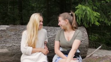 Kadınlar üzerinde büyük bir günlük ormanı kenarında oturan konuşuyor