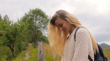 Kameraya poz ve orman ve dağ köyü bir arka plan üzerinde gülümseyen güzel kız