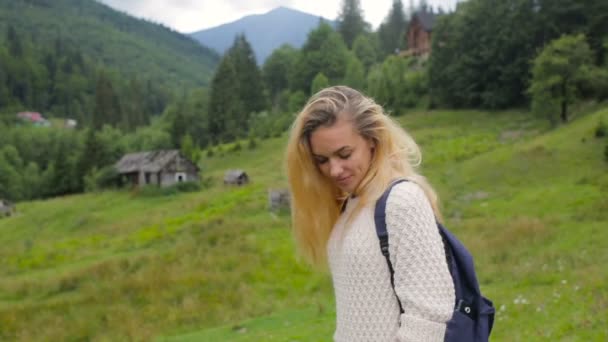 漂亮的女孩在照相机摆姿势，森林和山区村庄的背景上微笑 — 图库视频影像
