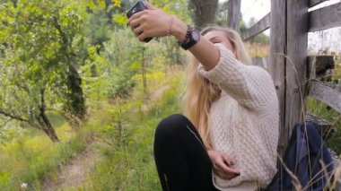 Bir kadının selfies bir dağ yolu üzerinde bir cep telefonunda yapması