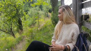 Genç, güzel bir kız bir çit yakınlarında bir dağ yolda rahatlatır ve suyu içer