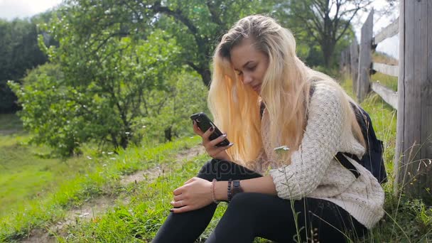 Женщина пользуется мобильным телефоном на горной дороге — стоковое видео