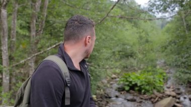 Genç bir adam ile bir dağ nehir üzerinde bir köprü üzerinde sırt çantaları