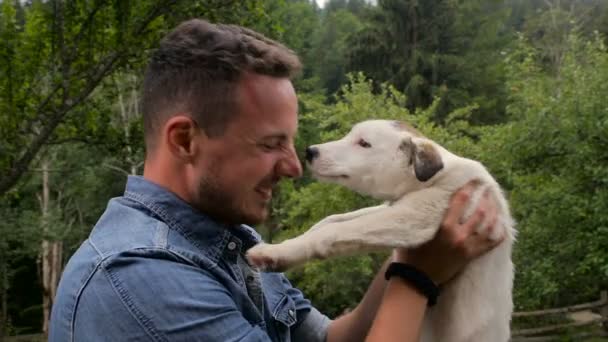 Junger schöner Mann spielt mit Welpen im Garten — Stockvideo