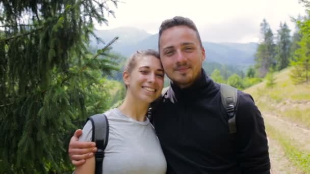 Couple de touristes posant et regardant la caméra sur le fond des montagnes — Video