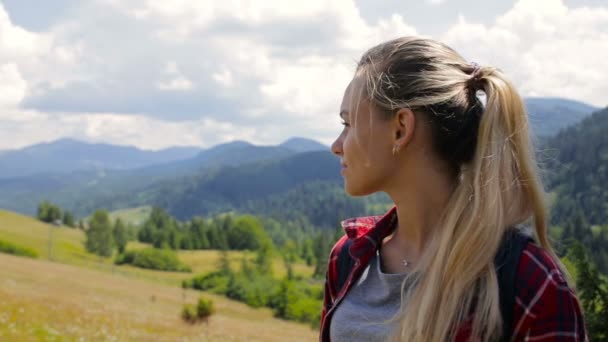 Крупный план портрет красивой молодой женщины, улыбающейся на фоне природы гор — стоковое видео