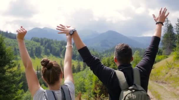 Un couple escalade une chaîne de montagnes, lève les mains pour la joie — Video