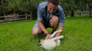 Bahçede köpek yavrusu ile oynayan genç yakışıklı adam