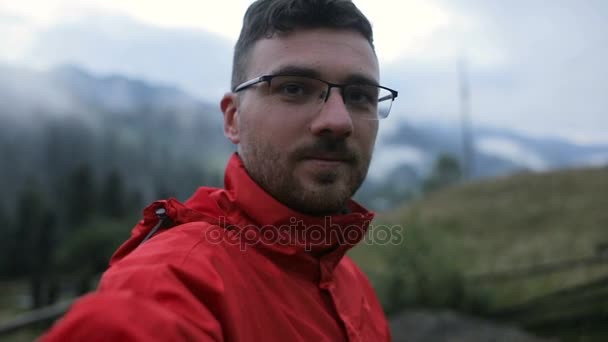 En ung man på kvällen i bergen gör selfy — Stockvideo