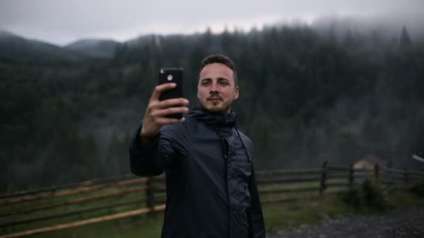 Un jeune homme dans la soirée dans les montagnes fait selfy — Video