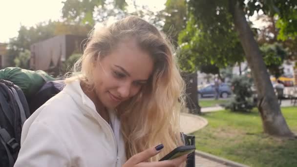 Touch telefon sms skriver, ung flicka på parkbänk — Stockvideo