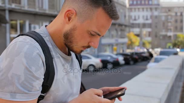 Mladý muž s plnovousem, sedí na schodech před a kontrola pošty na mobilní telefon — Stock video