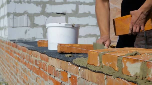 Werk legt bakstenen op een bouwplaats op open lucht — Stockvideo