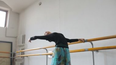 Profesyonel balerin, bir bale barının yanında pratik yapıyor.