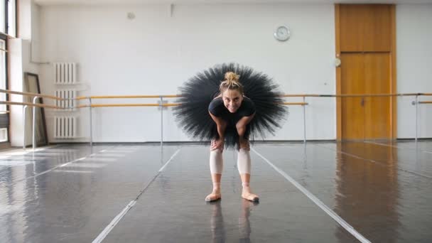 Egy profi balerina fekete falkában táncol egy nagy edzőteremben — Stock videók