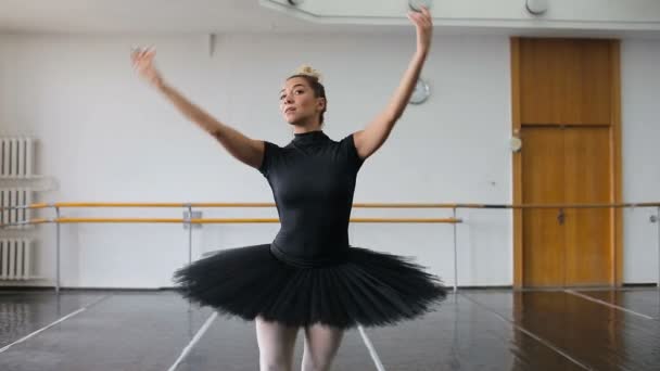 Профессиональная балерина в черном стае танцует в большом тренировочном зале — стоковое видео