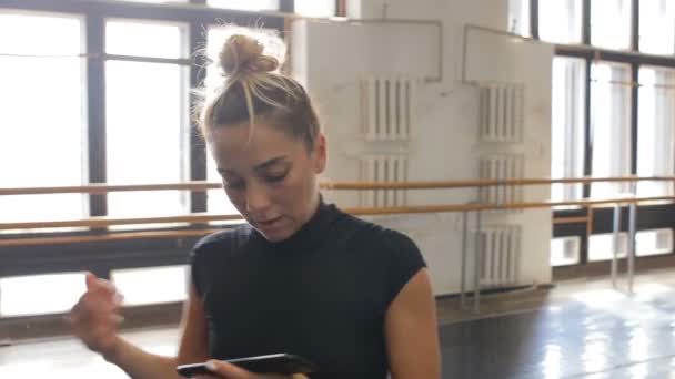 La bailarina practica en el gran salón y escucha música en el smartphone — Vídeos de Stock