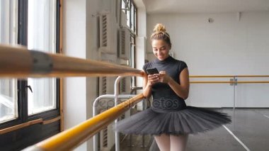 Bir balerin bir smartphone bir büyük eğitim salonunda kullanır.