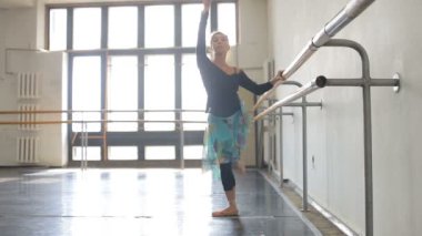 Profesyonel balerin, bir bale barının yanında pratik yapıyor.