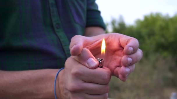Крупным планом лица рука зажигает огонь на зажигалку. яркий пламя зажигалки в замедленной съемке — стоковое видео