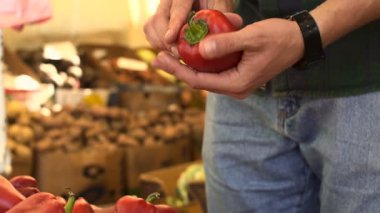 Genç adam ellerini biber meyve Pazar seçimi görünümünü kapat