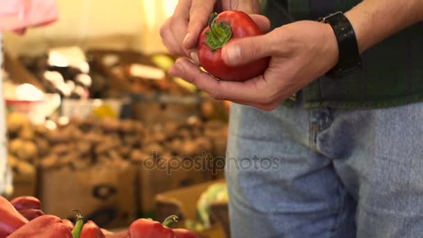 Vista de cerca de las manos del hombre joven la elección de la pimienta en el mercado de frutas — Vídeo de stock