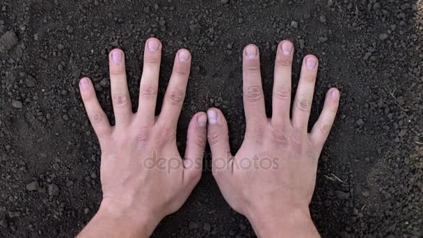 Закрытие руки человека, делающего отпечаток руки на черной земле — стоковое видео
