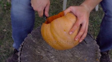Adam bir kabak Jack-o-fener bahçede bir ağaç kütüğü üzerinden açmaktadır