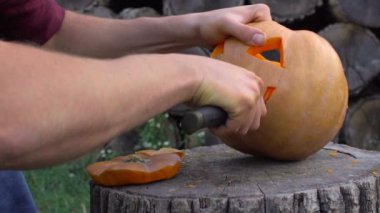 Adam bir kabak Jack-o-fener bahçede bir ağaç kütüğü üzerinden açmaktadır